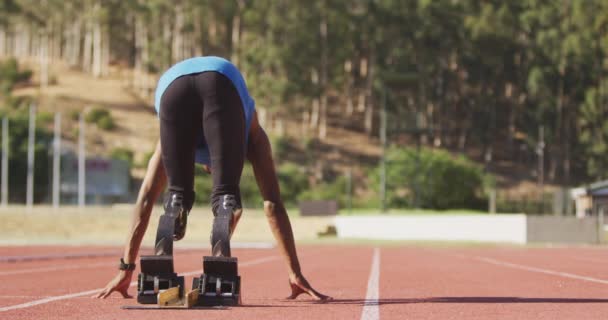 陸上競技場のランニングコースに義足をつけた障害者混合レース男子アスリートがスローモーションでレースを開始する姿をリアビュー — ストック動画