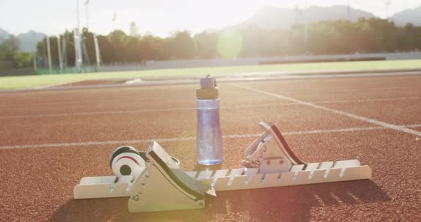Startblokker Flaske Vann Hodetelefoner Tilhørende Atlet Som Solen Utendørs Løpebane – stockvideo