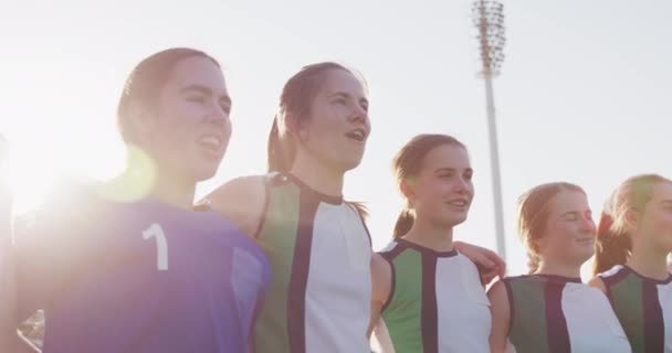 10代の白人女性ホッケーチームのクローズアップは スポーツスタジアムでピッチに立ち 腕を組んでホッケーの試合前に歌い スローモーション — ストック動画