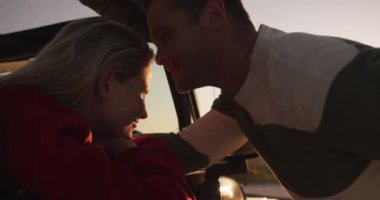 Güneşli bir yolculukta, doğada boş vakit geçirmeyi seven mutlu beyaz çifti yakından çek. Gün batımında gülümseyen bir adam ağır çekimde kadını öpüyor. Tatil aşkı boş zaman.