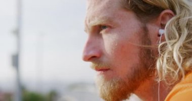 Şehirdeki bir yaya köprüsünde egzersiz yapan genç bir beyaz adam yavaş çekimde kulaklıkla müzik dinliyor. Sağlıklı kentsel aktif yaşam biçimi.