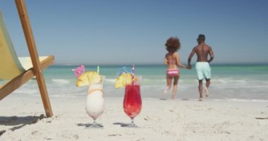 Afrika kökenli Amerikalı bir çiftin tropikal bir plaj tatilinde el ele tutuşup ağır çekimde denize koştuğunu görüyoruz. Plaj tatili eğlence aktiviteleri