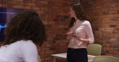 Kafkasyalı iş kadını iş arkadaşlarıyla birlikte modern bir ofiste çalışıyor, video görüşmesi sırasında beyin fırtınası yapıyor, elinde dijital tablet var. İş yaratıcılığı teknolojisi.
