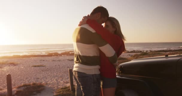 幸せな白人のカップルは 一緒にロードトリップの晴れた日に自然の中で自由な時間を楽しんで ゆっくりとした動きで日没で彼らの車に立って笑顔を受け入れます ホリデーロマンスレジャー — ストック動画