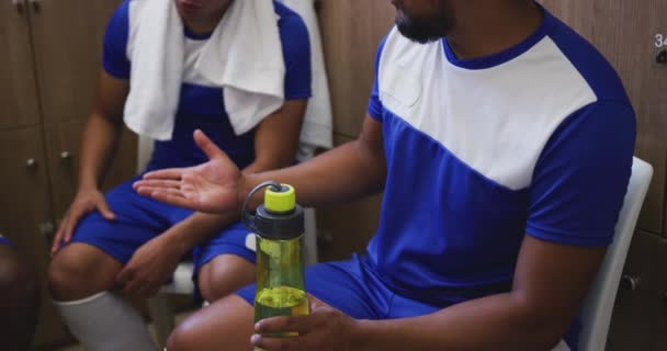 Dois Jogadores Futebol Mestiços Camarim Conversando Segurando Garrafa Água Câmera — Vídeo de Stock