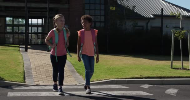 白人とアフリカ系アメリカ人の女の子が横断歩道で道路を横断し スローモーションで通学している 小学生 道路安全 — ストック動画