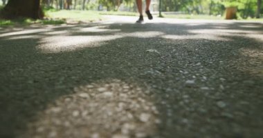 Parkta spor kıyafetleri içinde ağır çekimde koşan, kıdemli, beyaz bir adamın düşük kesimi. Emeklilik sağlıklı yaşam tarzı aktivitesi.