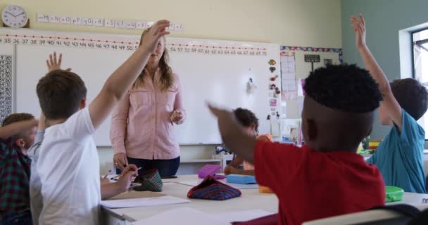 多种族的儿童和他们的白人女教师坐在教室里上课 孩子们举手 慢动作 小学的教育 — 图库视频影像