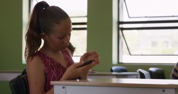 Kaukasisches Mädchen Das Einem Schreibtisch Klassenzimmer Sitzt Ein Smartphone Benutzt — Stockvideo