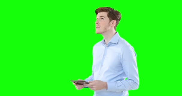 自信に満ちたハンサムな白人男性茶色の髪 薄い青のシャツを着て 笑顔と緑の画面の背景に彼のタブレットを使用して — ストック動画