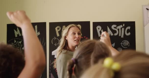 Többnemzetiségű Gyerekek Kaukázusi Tanárnőjük Poszterekre Mutogatnak Újrahasznosítható Anyagokról Beszélgetnek Felemelik — Stock videók