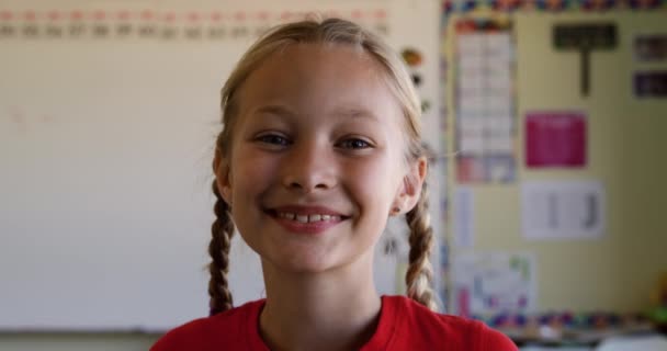 レッスン中に教室に座っている白人の女の子の肖像画 カメラを見て笑顔 スローモーションで 小学校での教育 — ストック動画