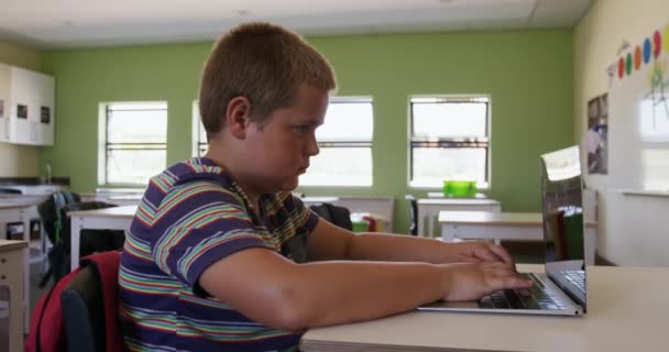 教室の机に座っている白人の少年は ラップトップコンピュータを使用して ゆっくりと動きます 小学校での教育は — ストック動画