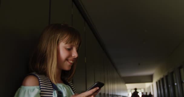 休憩中に廊下に立って白人の女の子 スマートフォンを使用して スローモーションで 小学校での教育 — ストック動画