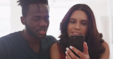 Karışık ırk adamıyla Kafkasyalı kadın birlikte vakit geçiriyorlar, hafta sonları evde dinleniyorlar, armut çuvalında oturuyorlar, birlikte akıllı telefon kullanıyorlar.