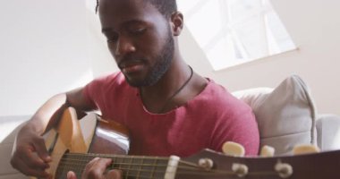 Hafta sonu evde dinlenen, kanepede oturup gitar çalan melez bir yarışçı. Karantina bölgesindeki sosyal mesafeler kilitlendi
