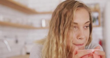 Beyaz kadın hafta sonları evde dinleniyor, mutfakta oturuyor, bir masanın kenarında çay içiyor. Karantina bölgesindeki sosyal mesafeler kilitlendi