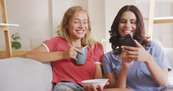 Two Caucasian Women Relaxing Home Weekend Sitting Sofa Eating Snacks — Stock Video