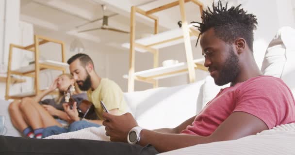 Mixed Race Man Relaxing Home Weekend Sitting Sofa Using Smartphone — Stock Video