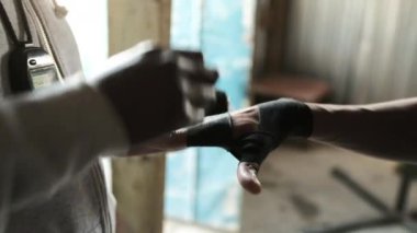 Afro-Amerikan erkek boksörün orta bölümü bir boks salonunda ellerini boynuna kronometre takmış Afrikalı Amerikalı bir erkek eğitmene sardırıyor.