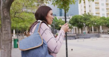 Kıvrımlı beyaz kadın gündüzleri şehir sokaklarında dolaşıyor ve yemek yiyor. Arka planda modern ofis binalarıyla birlikte ağır çekimde..