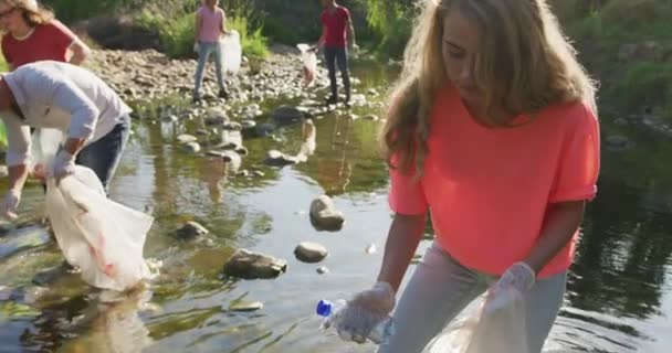 在一个阳光明媚的夜晚 一个白人妇女和一群环保志愿者在乡间清理河流 捡垃圾 农村环境中的生态和社会责任 — 图库视频影像