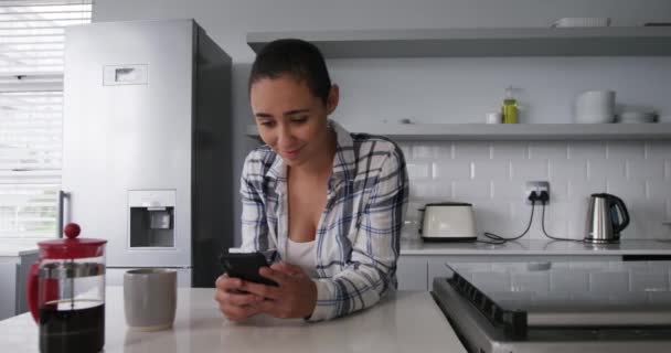 인종인 여자가 집에서 시간을 즐기고 커피를 마시고 부엌에서 스마트폰을 사용하고 — 비디오