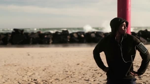아프리카 미국인 남자는 해변에서 운동을 즐기고 휴식을 취하고 장대에 기대어 — 비디오