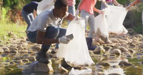 在阳光灿烂的日子里 非裔美国人和一群环保志愿者正在清理一条河 捡垃圾 农村环境中的生态和社会责任 — 图库视频影像