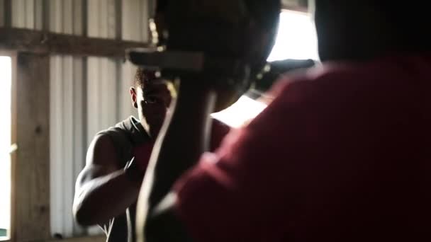 从肩膀上看非裔美国男性拳击手身穿拳击手套训练在乡镇拳击馆向一名身穿冲刺垫的非裔美国男性教练扔拳 动作缓慢 — 图库视频影像