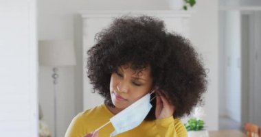 Afro saçlı, maske takan ve kameraya gülümseyen mutlu Afrikalı Amerikalı kadın portresi. Coronavirus Covid 19 karantina sürecinde sosyal uzaklık ve kendini izole etme.