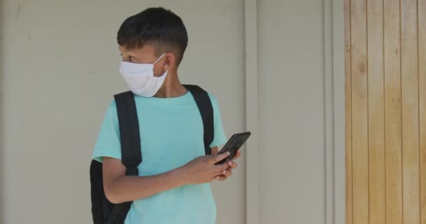 Vit Pojke Som Använder Sin Smartphone Bär Ansiktsmask Skolan Grundutbildning — Stockvideo