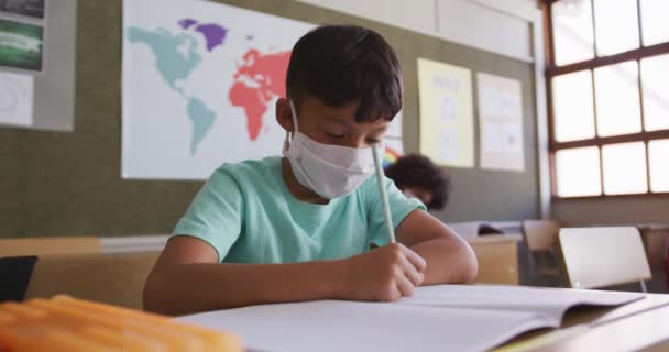 Hvid Dreng Skriver Bog Iført Ansigtsmaske Mens Han Sidder Sit – Stock-video