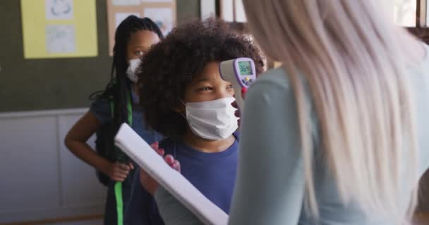 소녀는 학교에서 마스크를 착용하고 체온을 했습니다 교육의 사회적 코로나 바이러스 — 비디오