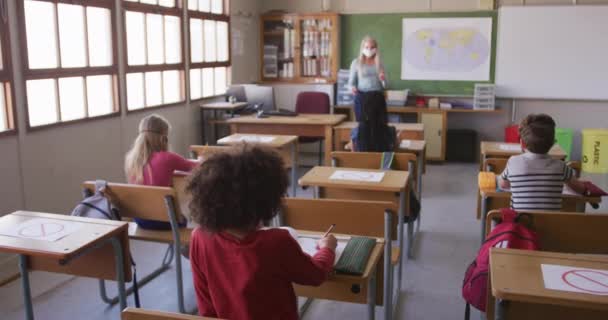 Gruppe Multietniske Børn Iført Ansigtsmasker Klasseværelset Skolen Hæve Hænder Primærundervisning – Stock-video