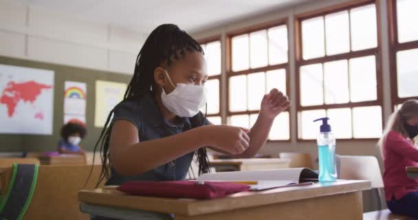 Ragazza Razza Mista Mettere Disinfettante Mano Indossando Maschera Mentre Seduto — Video Stock