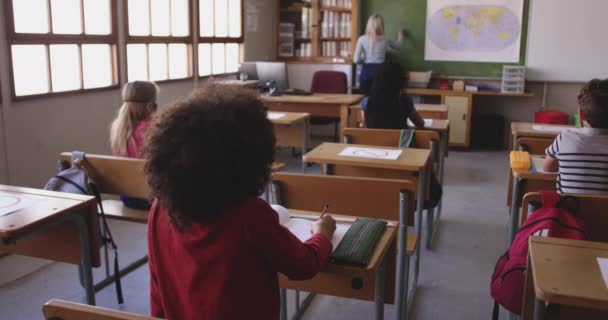 学校の教室では マスクを着て 複数の民族の子供たちのグループ Covid19時の初等教育社会的距離の健康上の安全性スローモーションでコロナウイルスパンデミック — ストック動画