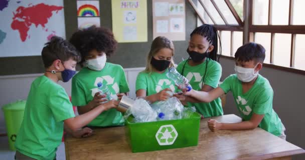 多族裔儿童穿着回收的T恤衫和面罩 在学校回收垃圾 Covid19 Coronavirus流感大流行期间 初等教育在社会上与健康安全保持距离的慢动作 — 图库视频影像