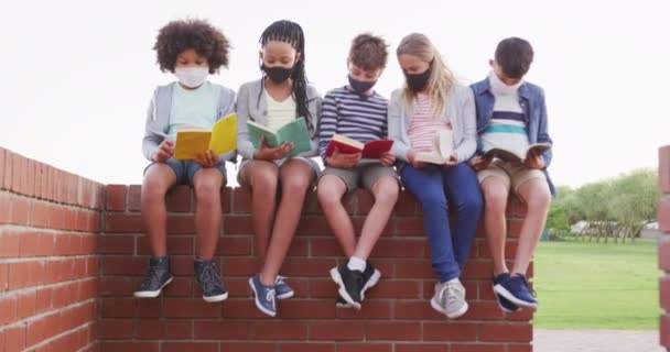 Skupina Mnohonárodnostních Dětí Obličejovými Maskami Kteří Čtou Knihy Sedí Zdi — Stock video