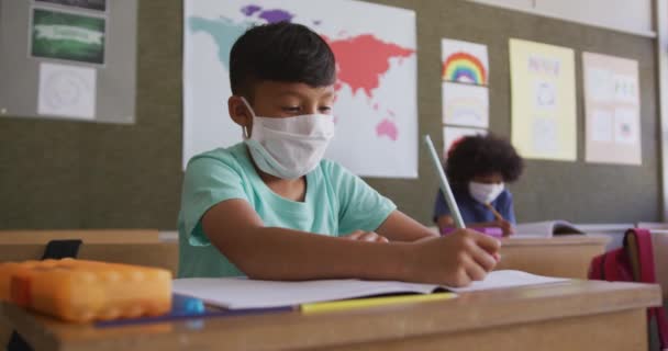 Blanke Jongen Schrijft Een Boek Draagt Gezichtsmasker Terwijl Hij Zijn — Stockvideo