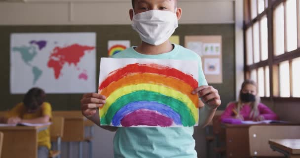 Anak Kulit Putih Mengenakan Masker Wajah Memegang Lukisan Pelangi Tersenyum — Stok Video