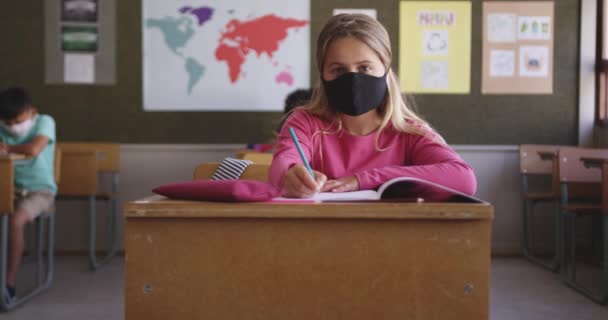 Ragazza Caucasica Che Scrive Libro Indossa Una Maschera Mentre Seduta — Video Stock