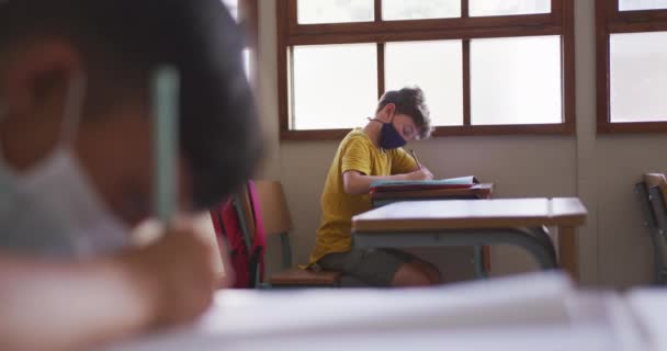 Kaukasischer Junge Mit Gesichtsmaske Der Der Schule Auf Seinem Schreibtisch — Stockvideo