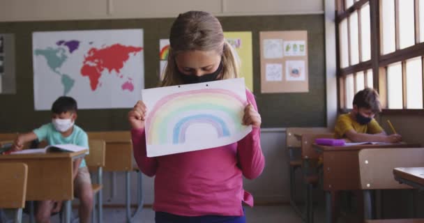 Vit Tjej Ansiktsmask Med Regnbågsmålning Och Leende Klassrummet Skolan Grundutbildning — Stockvideo