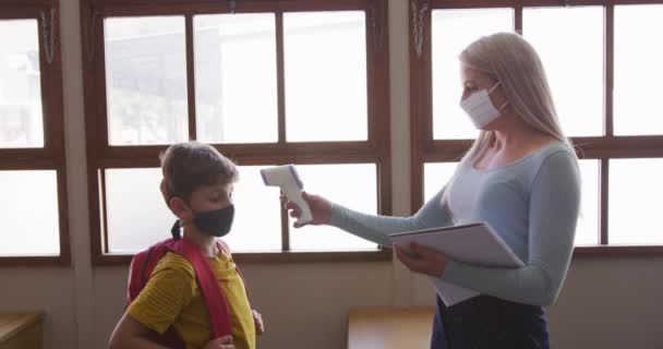 Kvindelige Lærer Iført Ansigtsmaske Måling Temperatur Børn Klasseværelset Skolen Primærundervisning – Stock-video