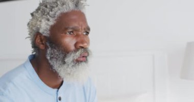 Yatak odasında bir yatakta oturan Afrikalı Amerikalı son sınıf öğrencisi, karantinada sosyal mesafeler ve kendini izole etme, yavaş çekim.