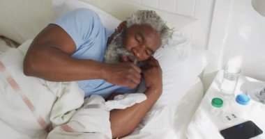 Afrika kökenli Amerikalı son sınıf öğrencisi yatak odasındaki bir yatakta uzanıyor. Yumruk, sosyal uzaklık ve karantina tecridinde kendini izole etme, yavaş çekim.