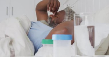 Afrika kökenli Amerikalı son sınıf öğrencisi yatak odasındaki bir yatakta uzanıyor. Yumruk, sosyal uzaklık ve karantina tecridinde kendini izole etme, yavaş çekim.