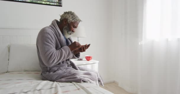 Hombre Mayor Afroamericano Sentado Una Cama Dormitorio Usando Teléfono Inteligente — Vídeos de Stock