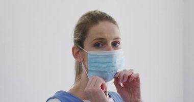 Beyaz kadın hemşire, maskesini takıyor. Covid 19 Coronavirus karantinası sırasında evde tıbbi bakım, yavaş çekim.